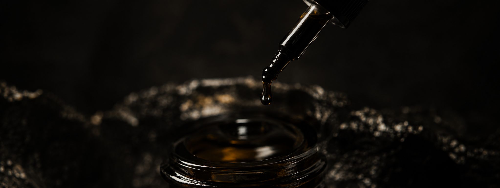 A single drop of shilajit falling from the glass dropper